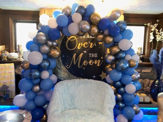a chair is surrounded by balloons and a sign that says over the moon