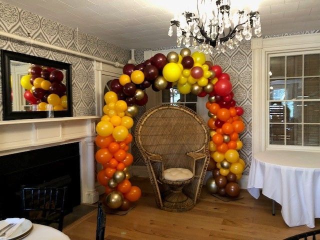 a room with a chair and a table decorated with balloons .