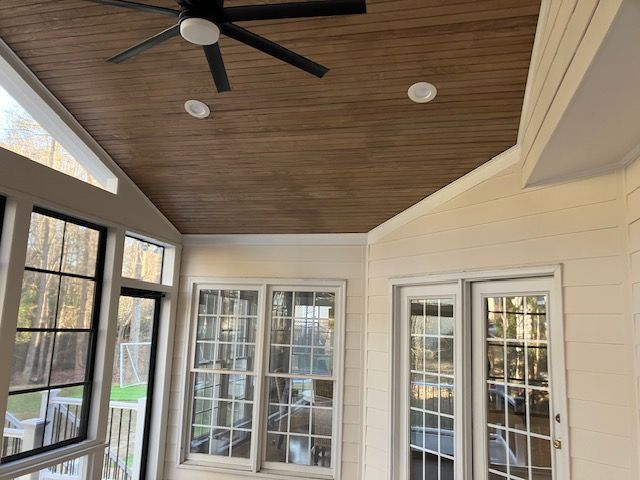 screened porch with a wooden ceiling, windows, and a ceiling fan