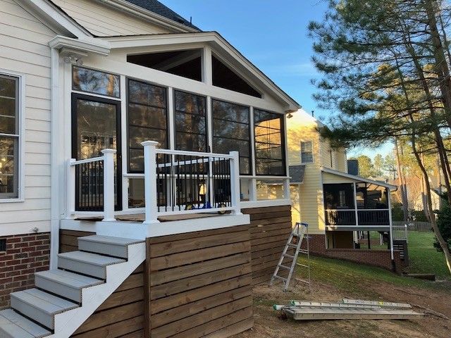 screened porch addition on a house with white railings, steps, and black framed screens