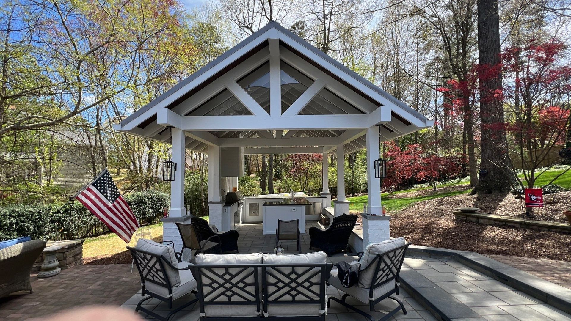 white gazebo with seating area in a backyard and an American flag