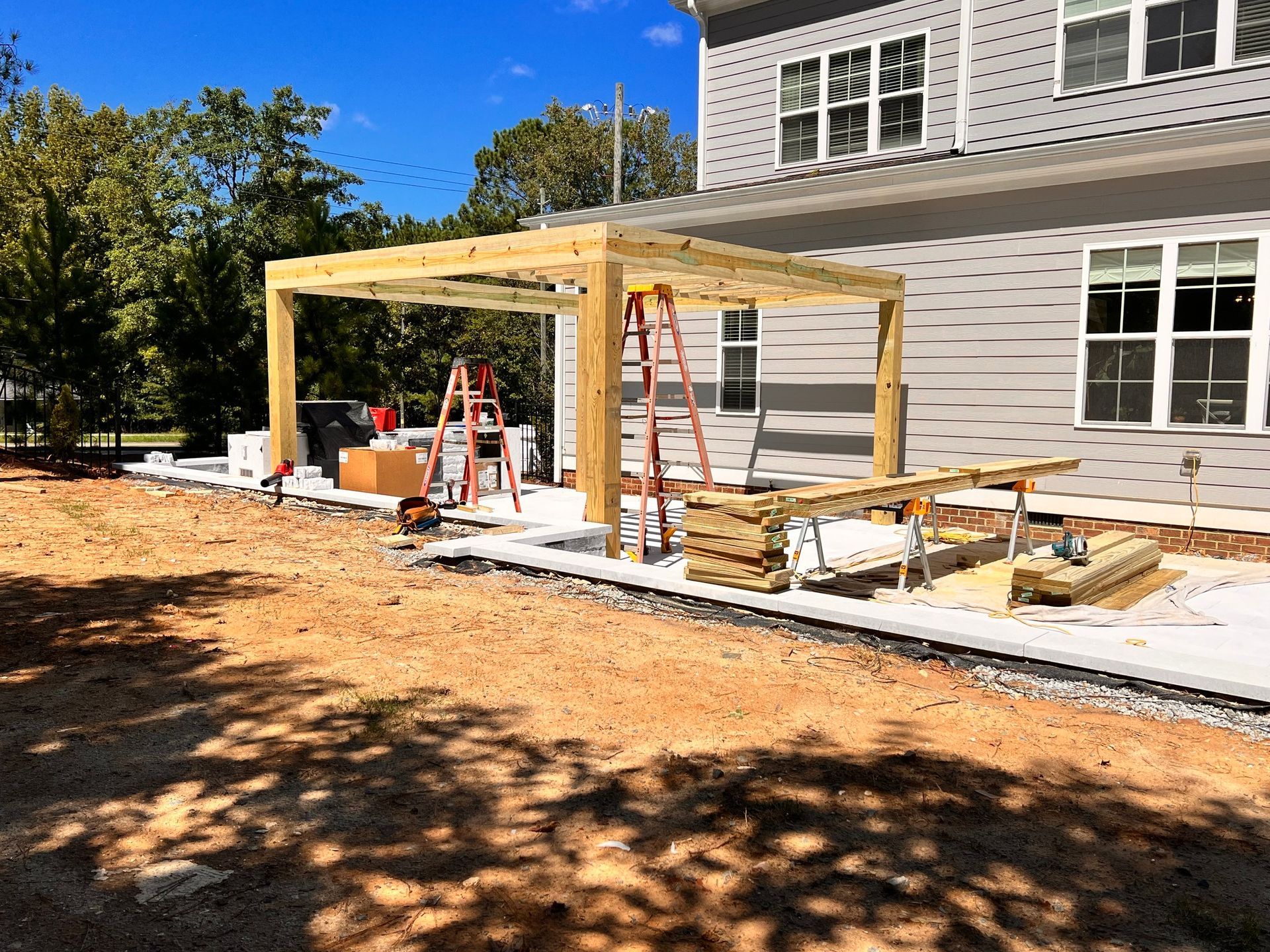 construction of a wooden pergola next to a gray house