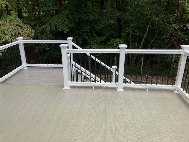 a deck with white railings, black spindles, and light gray decking