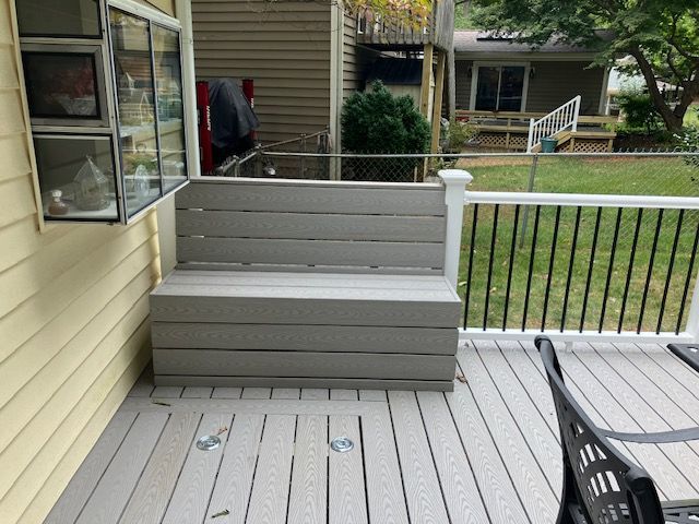 a bench on a deck, next to a white railing