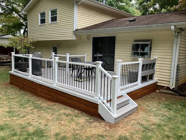 two-story home with a wooden deck that has white railings, black spindles, and a set of stairs