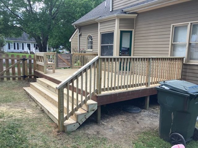 wooden deck with stairs and railing attached to a tan house