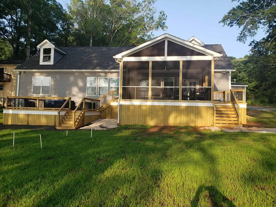 back view of a gray house with a screened porch and wooden deck