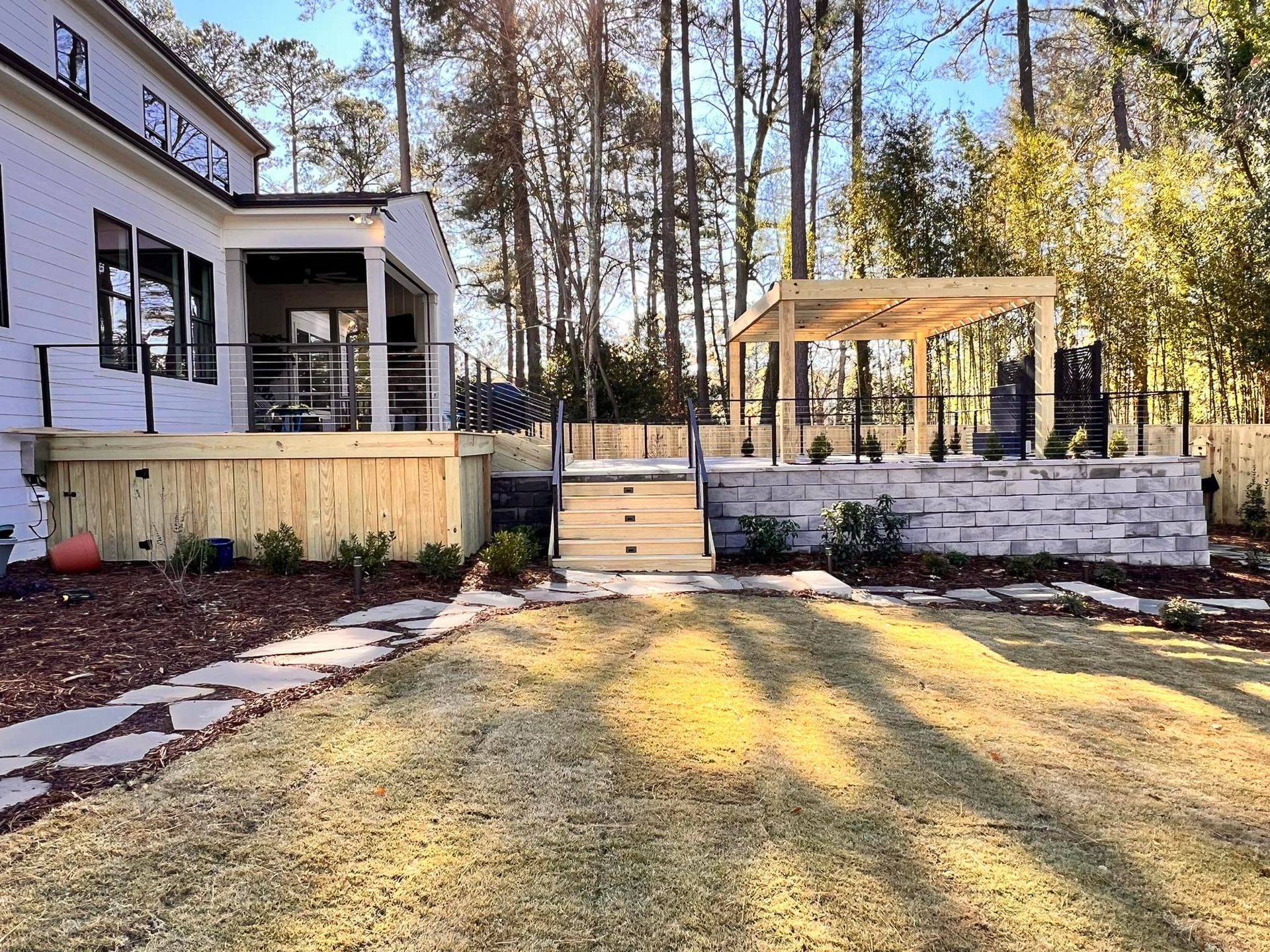 backyard with a deck, stone patio, pergola, and a large house