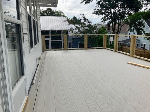 gray composite deck with wooden railing and surrounding houses