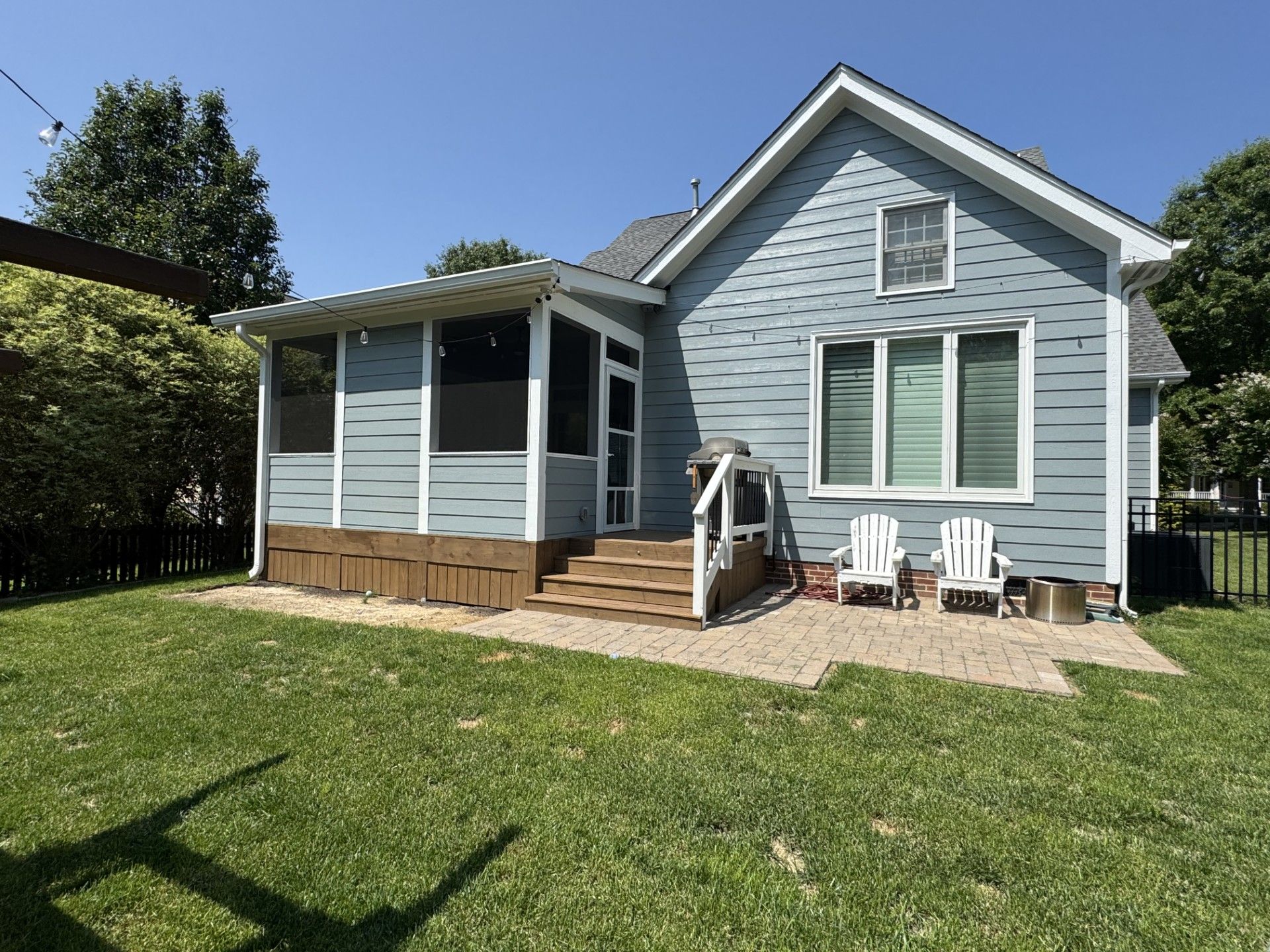 A small house with a screened in porch and chairs in front of it