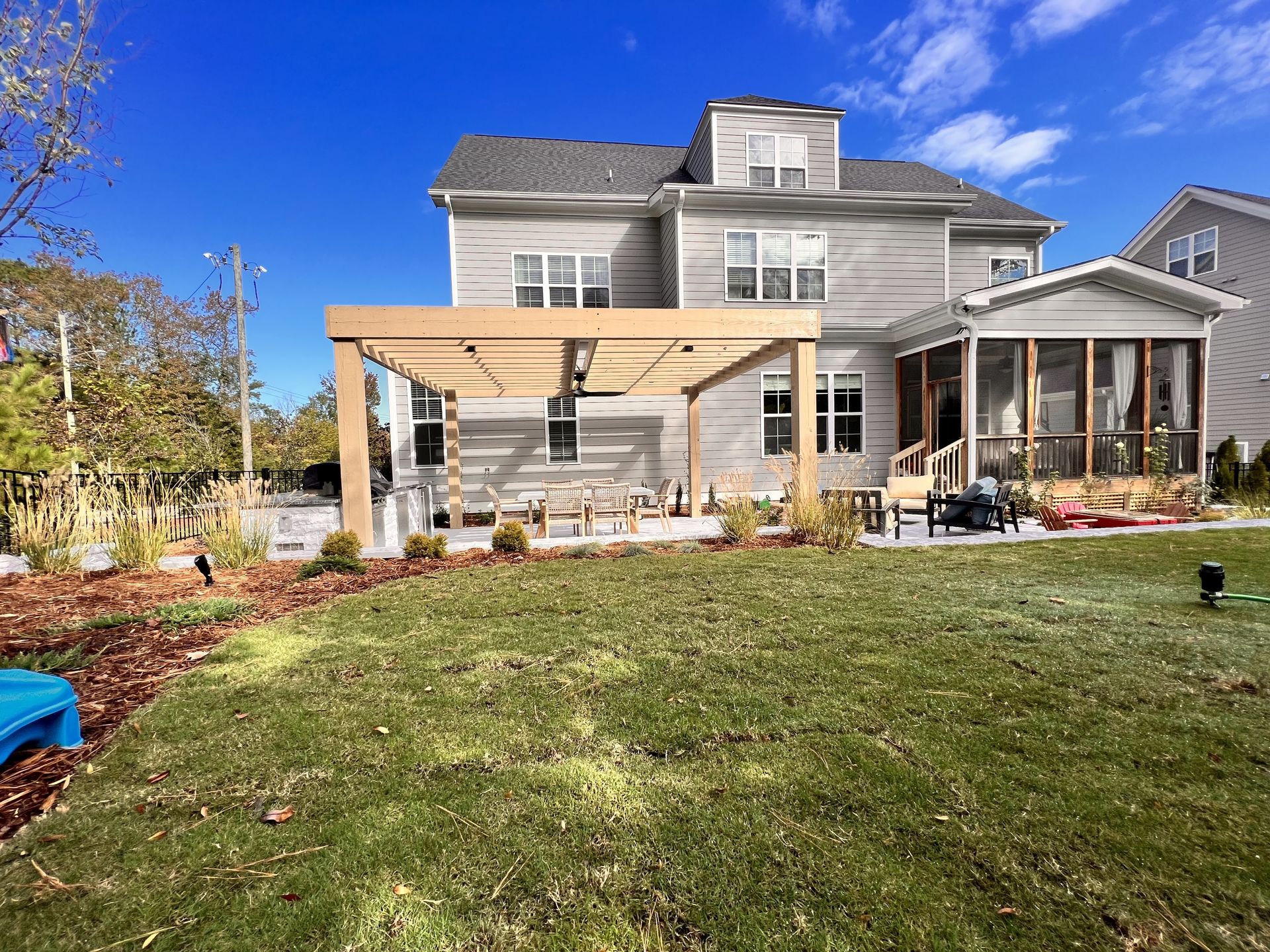 The backyard of a house with a pergola and a screened in porch