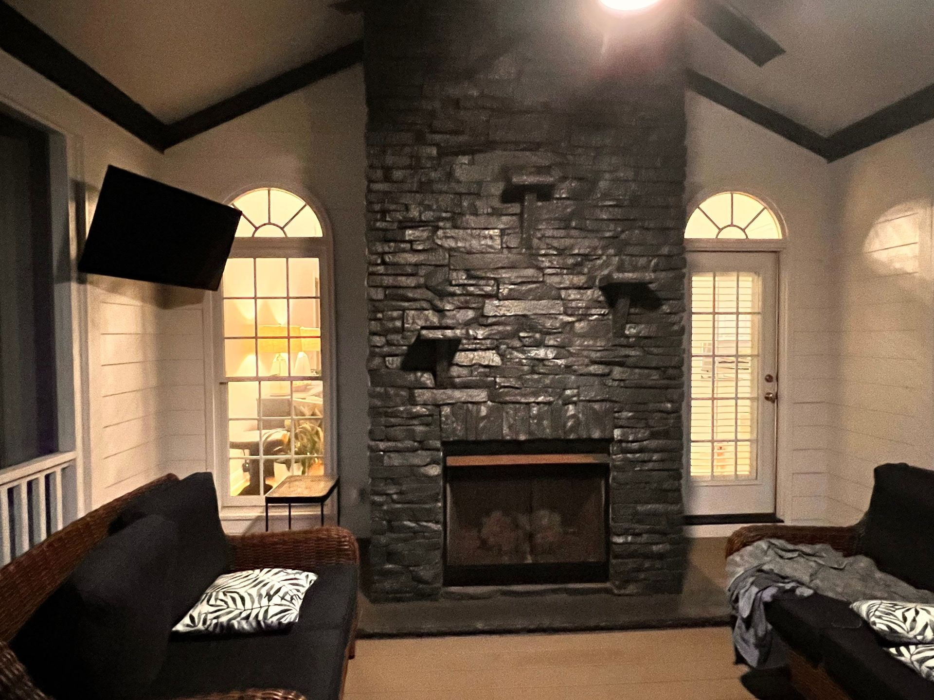 A living room with a stone fireplace and a flat screen tv