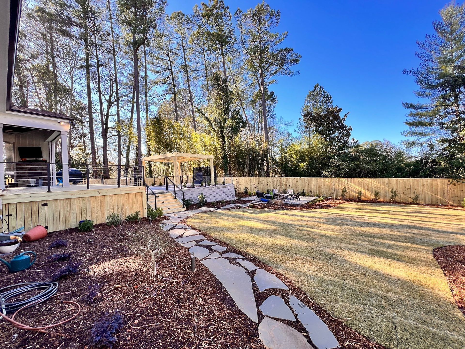 A backyard with a stone walkway leading to a house and a fence