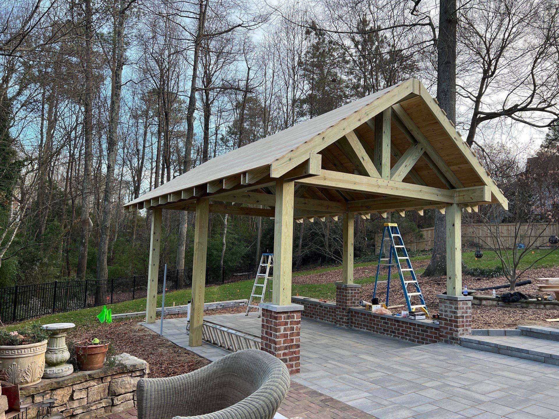 A wooden pavilion is being built in the backyard of a house