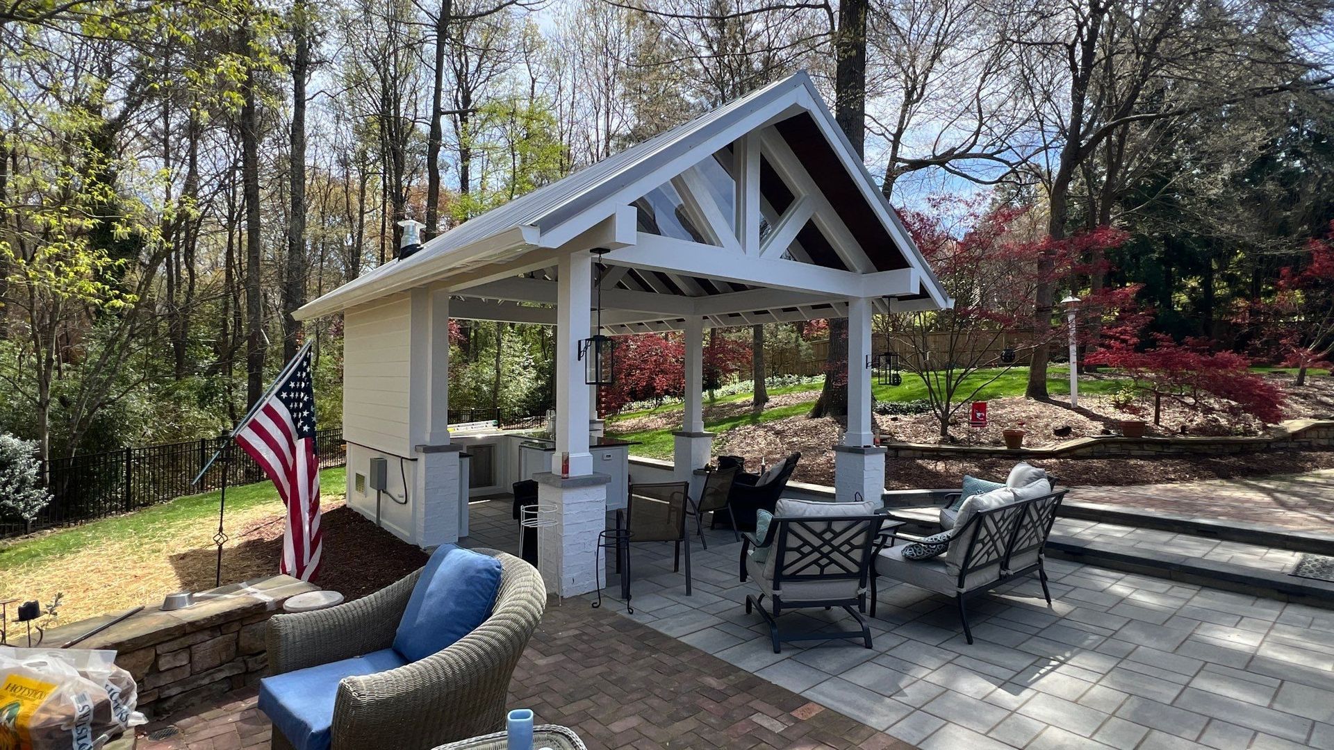 There is a gazebo with a flag on it in the middle of the woods