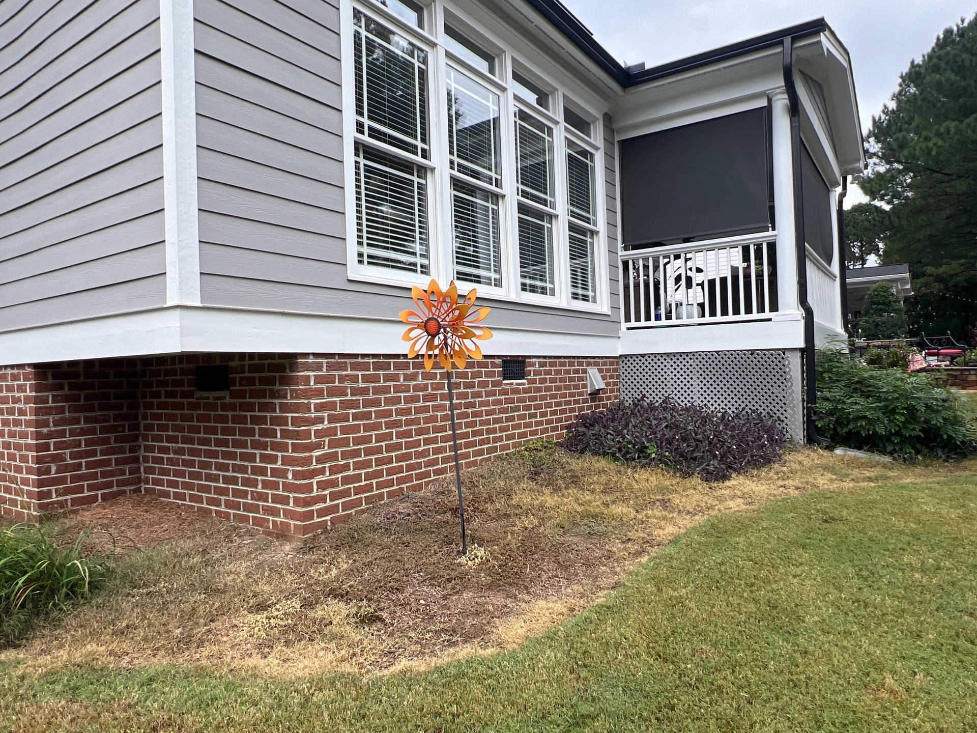 A house with a screened in porch and a tree in front of it.
