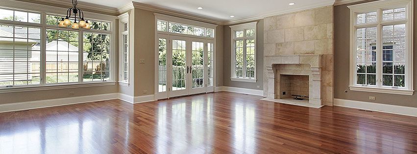 empty living room with hardwood floors, large windows, and a fireplace