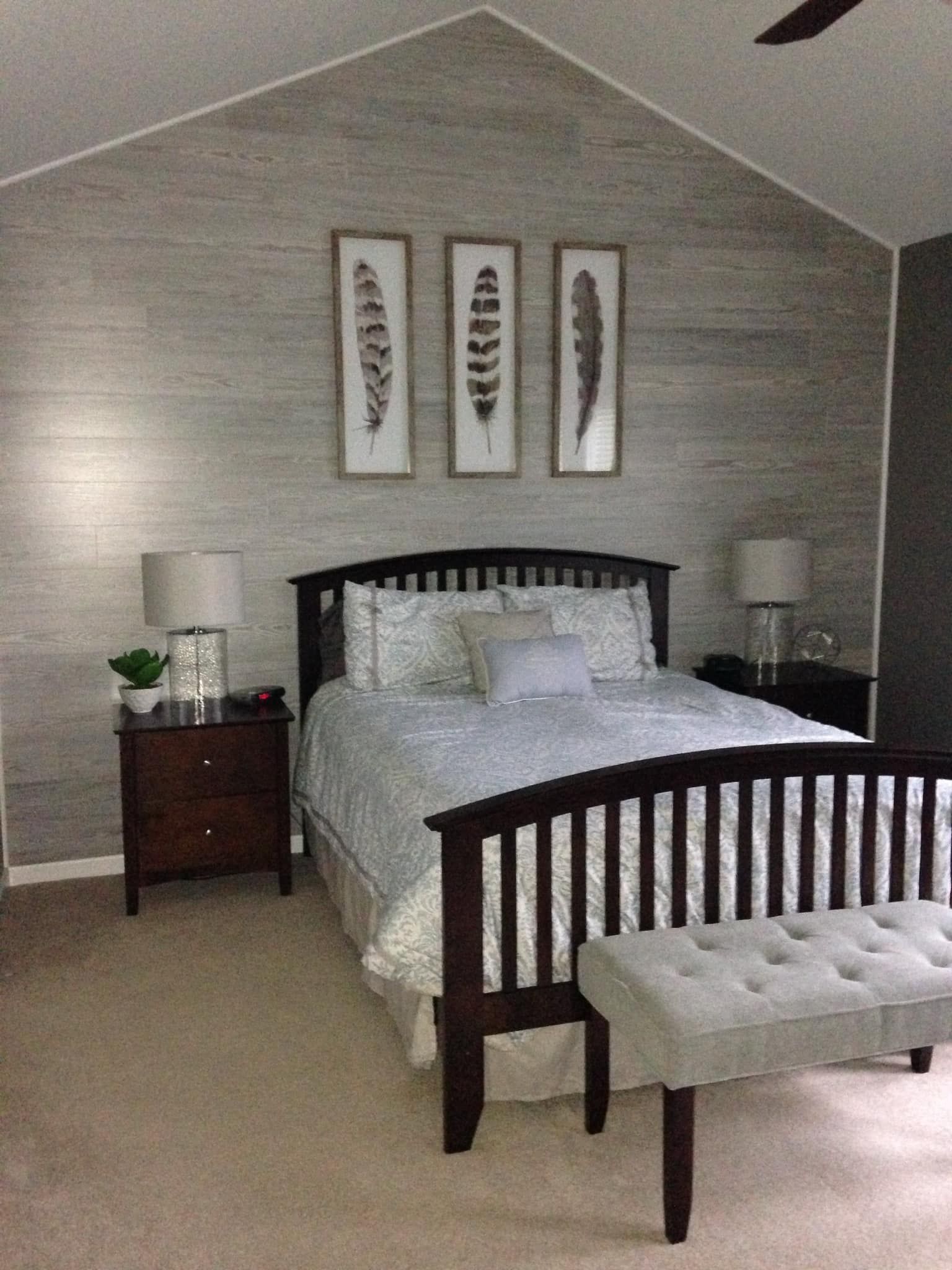 bedroom with gray wall, bed, nightstands, feather art, and bench