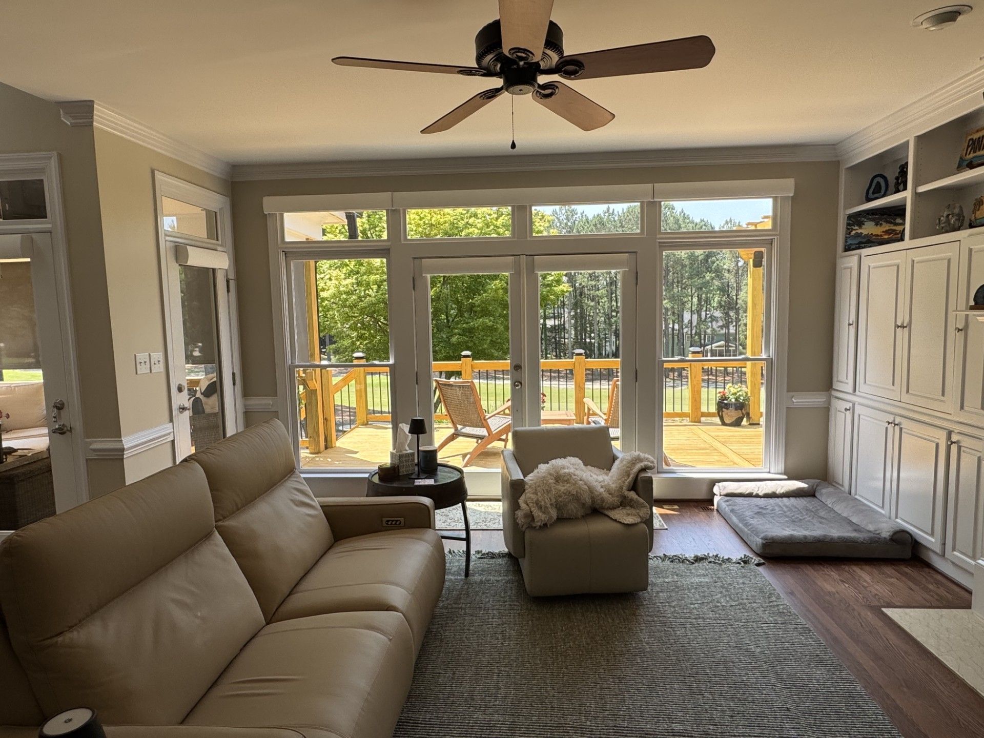 living room with tan sofa, armchairs, large windows overlooking a deck