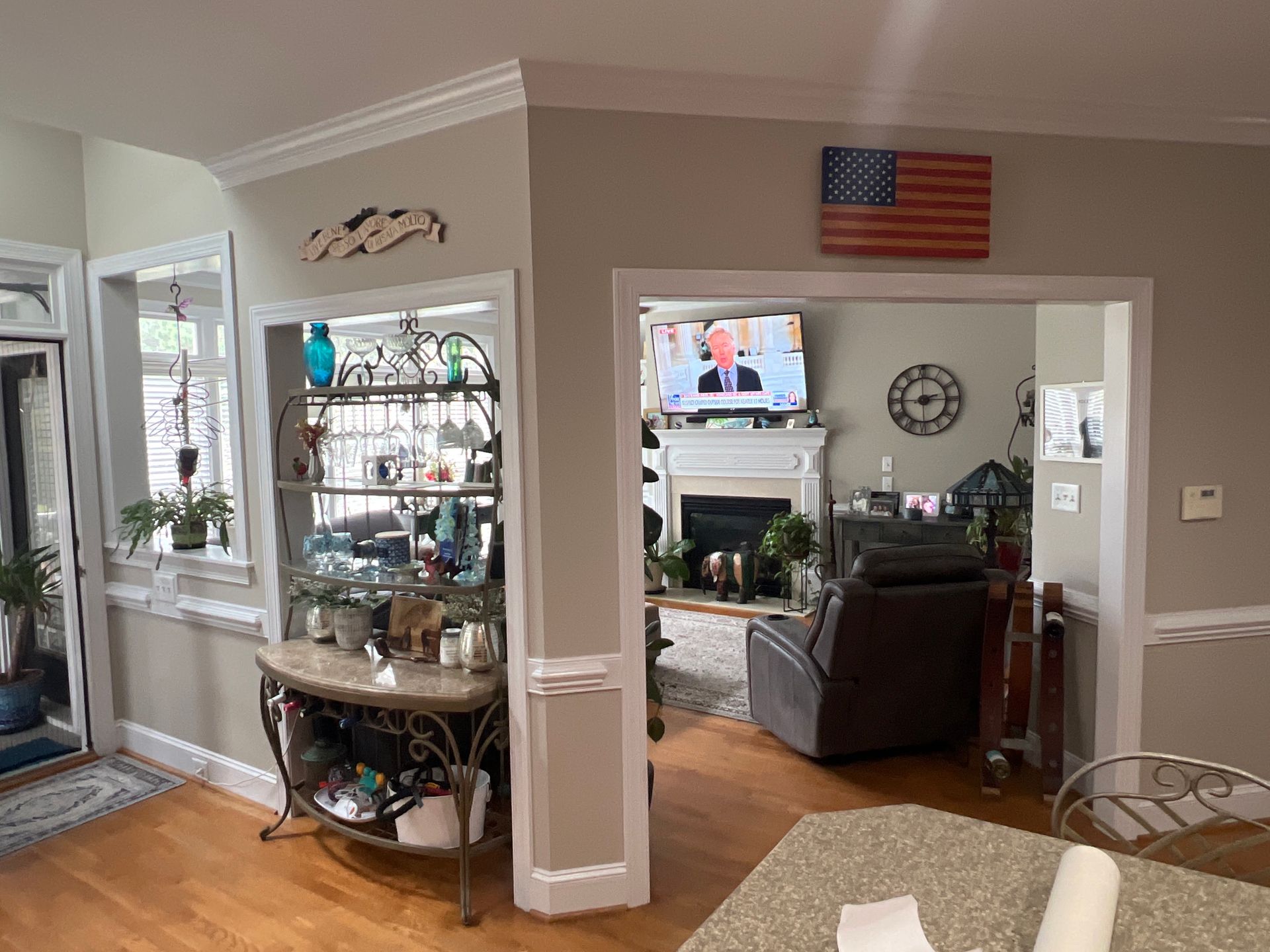A room with a shelf, television, and an American flag on the wall, with tan walls and hardwood floors