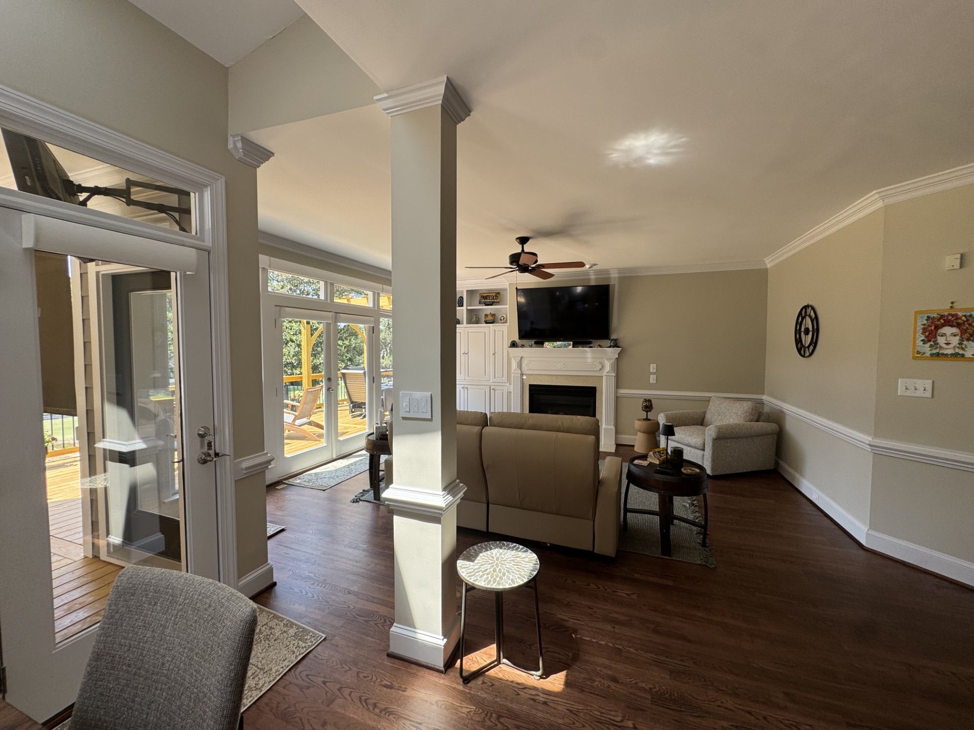 Interior view of a living room with a fireplace, tan walls, hardwood floors, and access to a patio