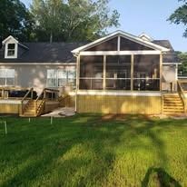 A mobile home with a screened in porch and deck.