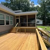 A house with a screened in porch and a wooden deck.