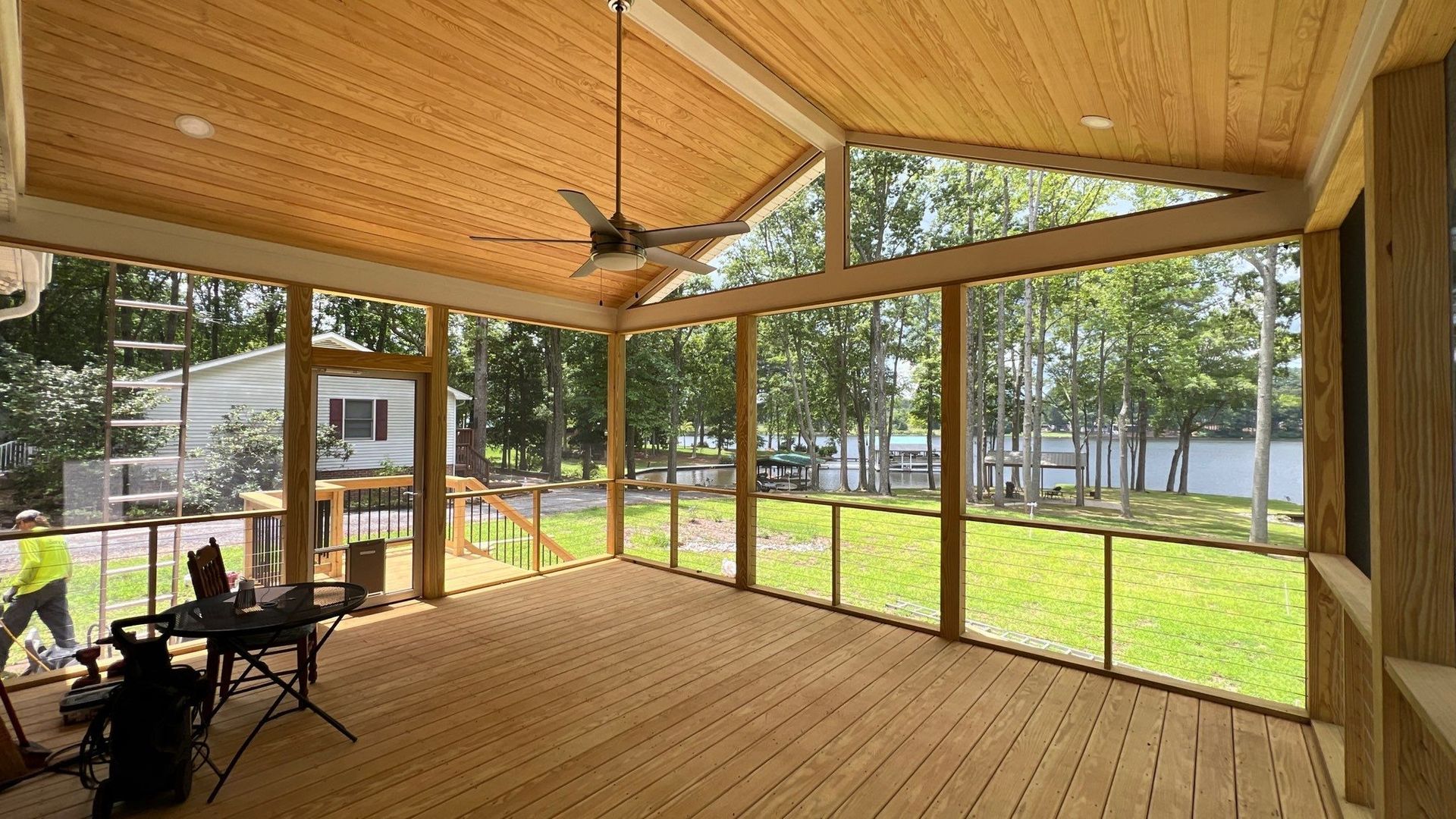 screened-in porch with wood ceiling and floor overlooking a lake