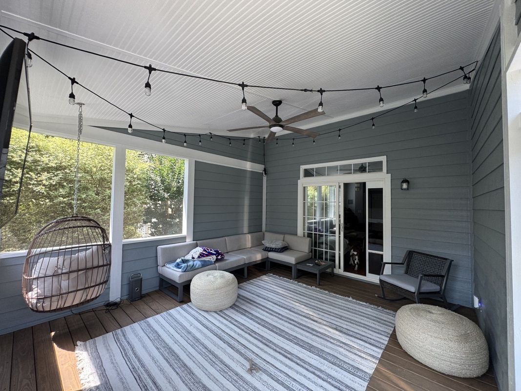outdoor patio with seating, string lights, ceiling fan, and hanging chair; gray walls, rug, and white trim