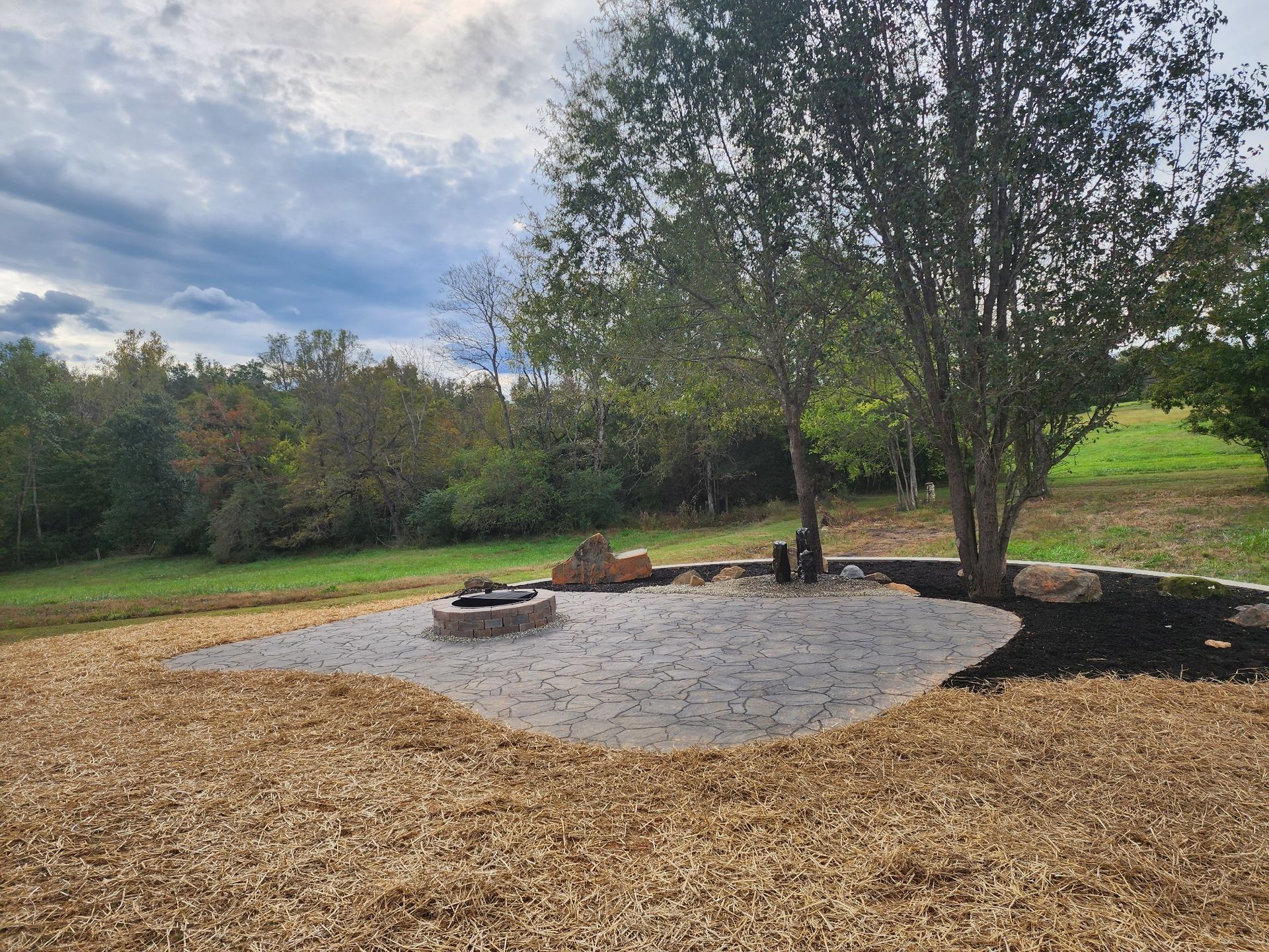A fire pit in the middle of a field with trees in the background.