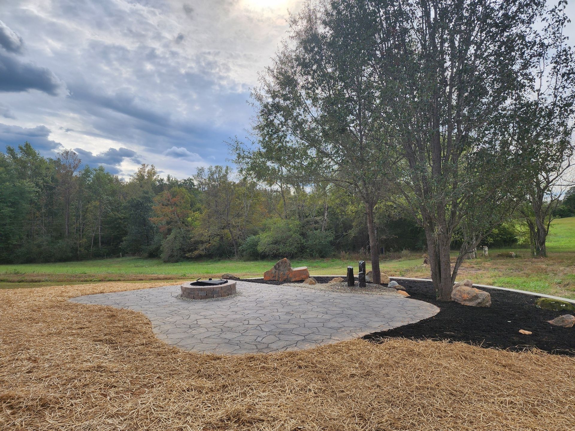 A fire pit in the middle of a field with trees in the background.