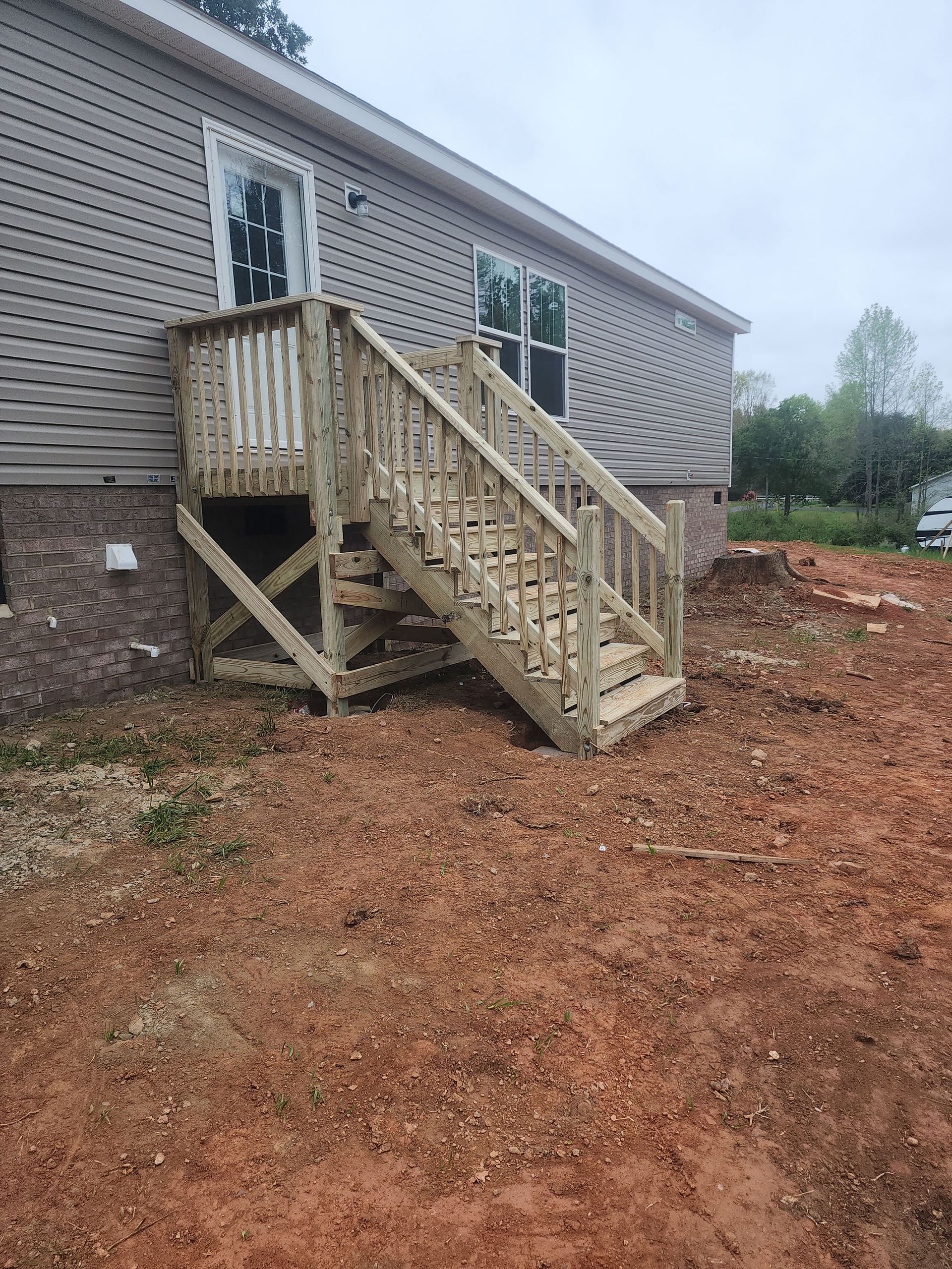 A wooden deck with stairs leading up to a mobile home.