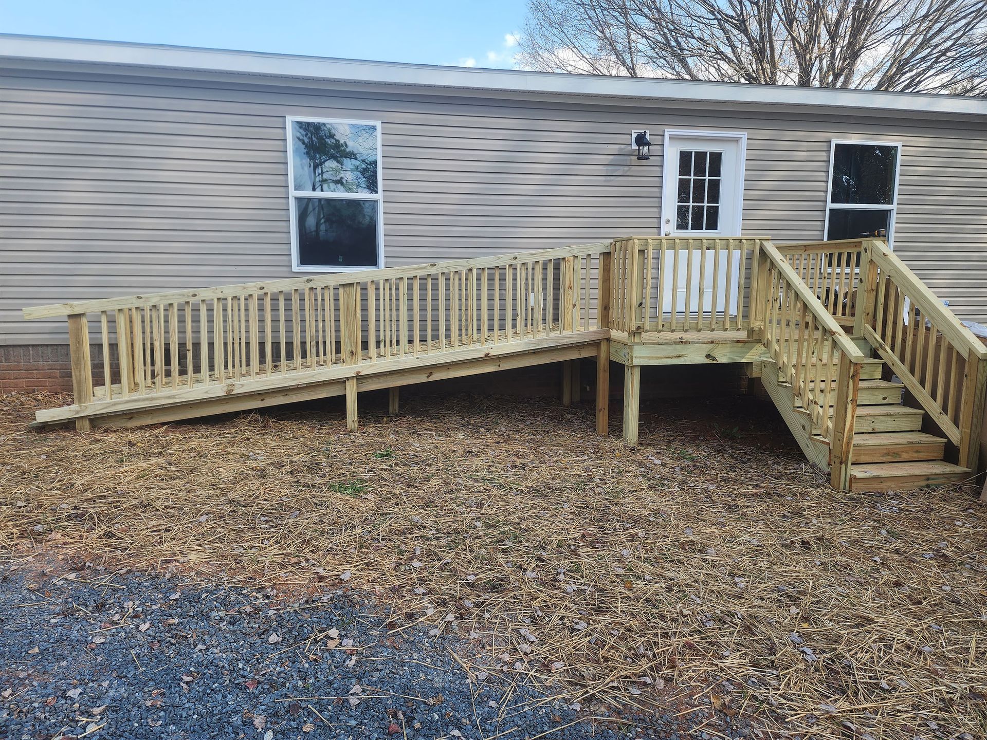 A mobile home with a wooden deck and ramp.