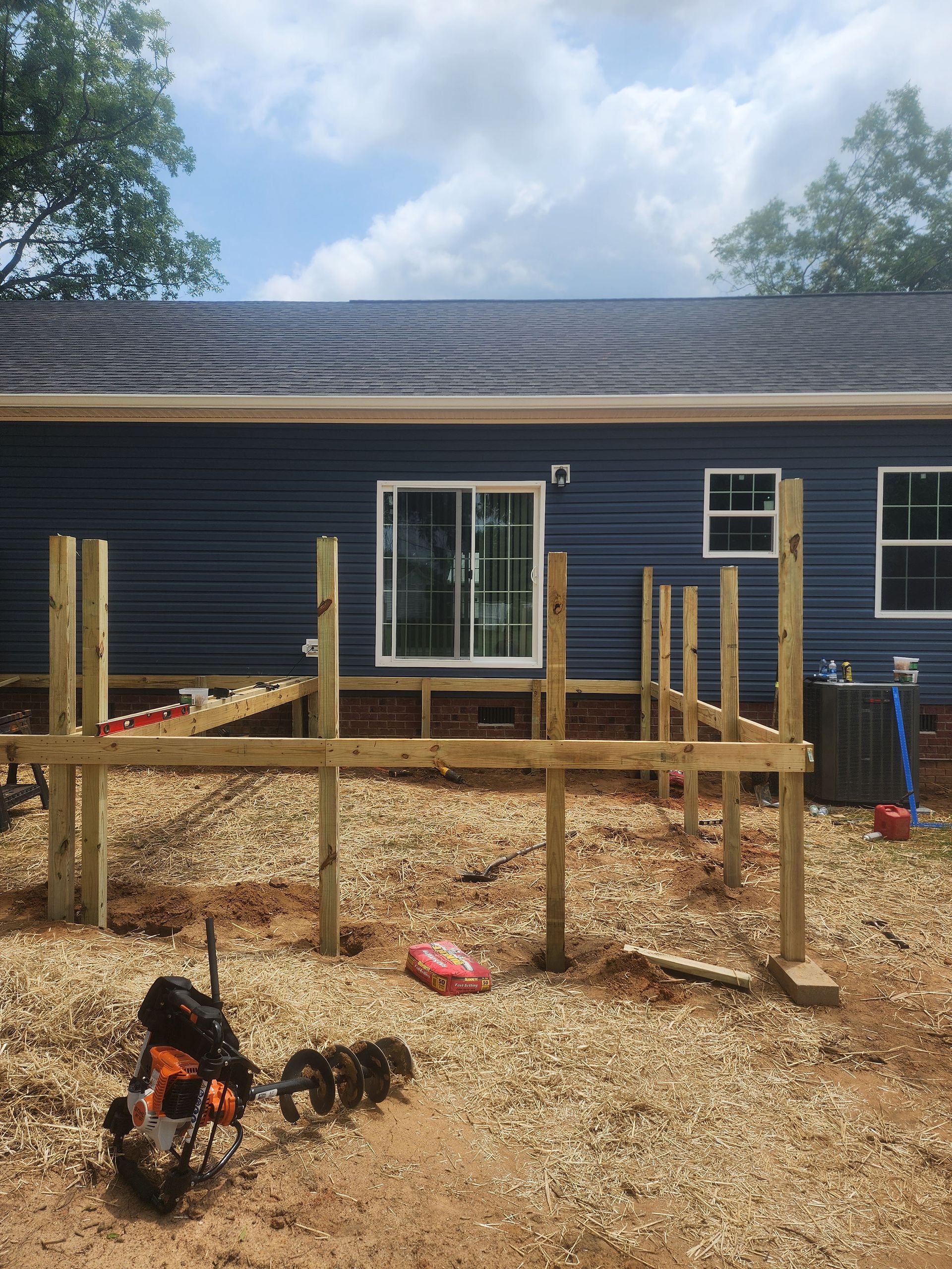 A blue house with a wooden deck being built in front of it.