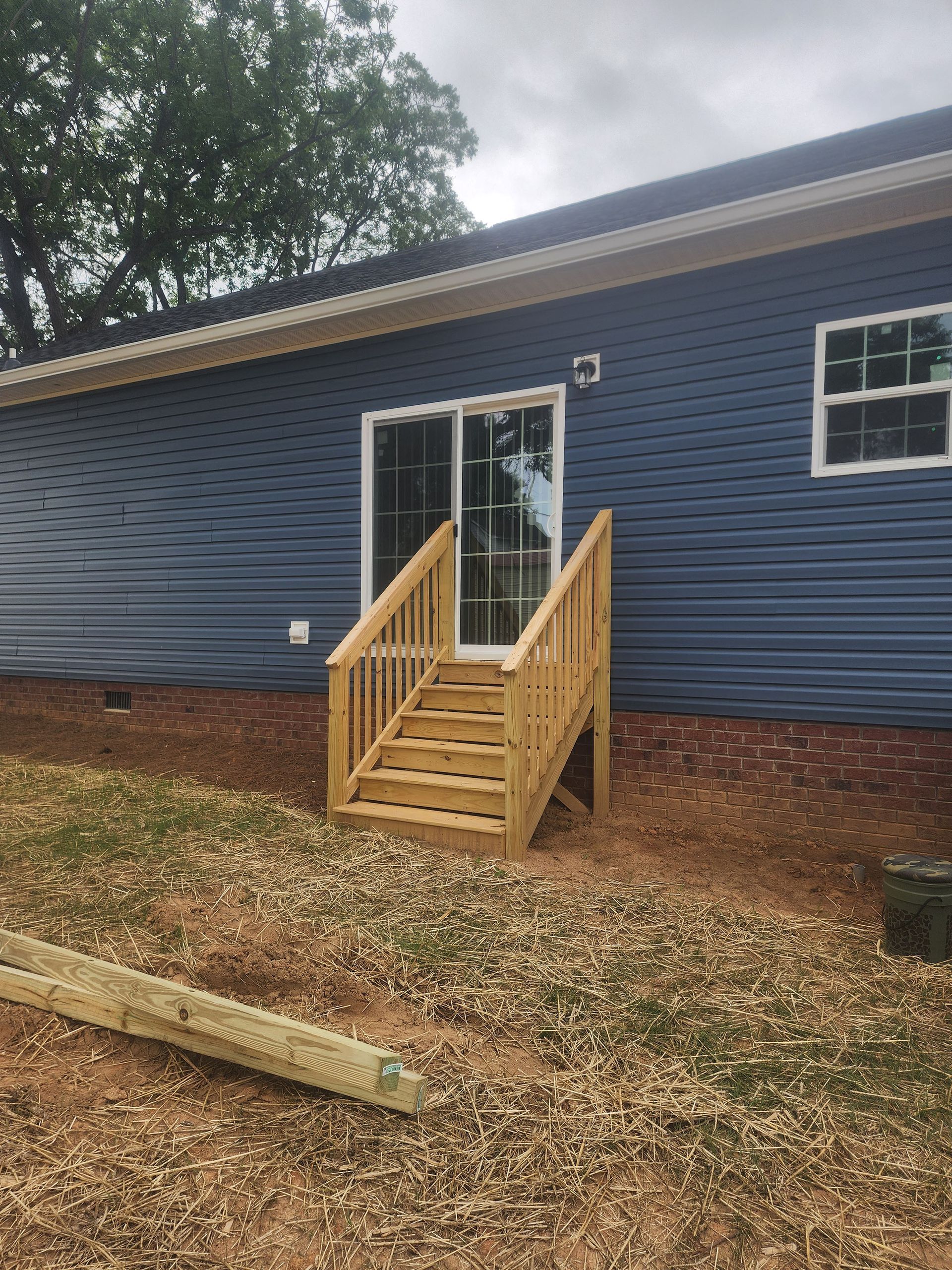 A blue house with a wooden deck and stairs in front of it.