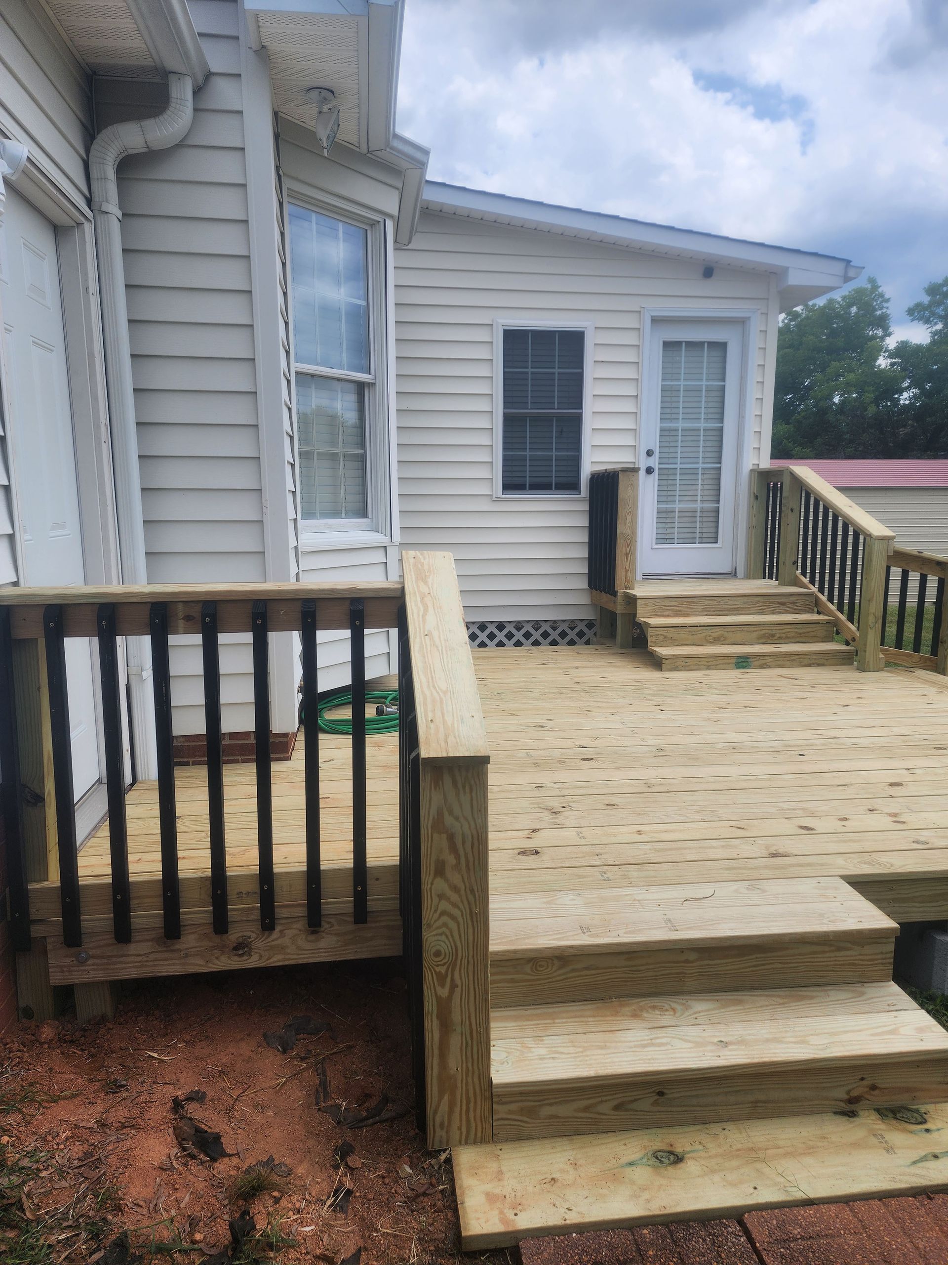 A wooden deck with stairs leading to a white house.