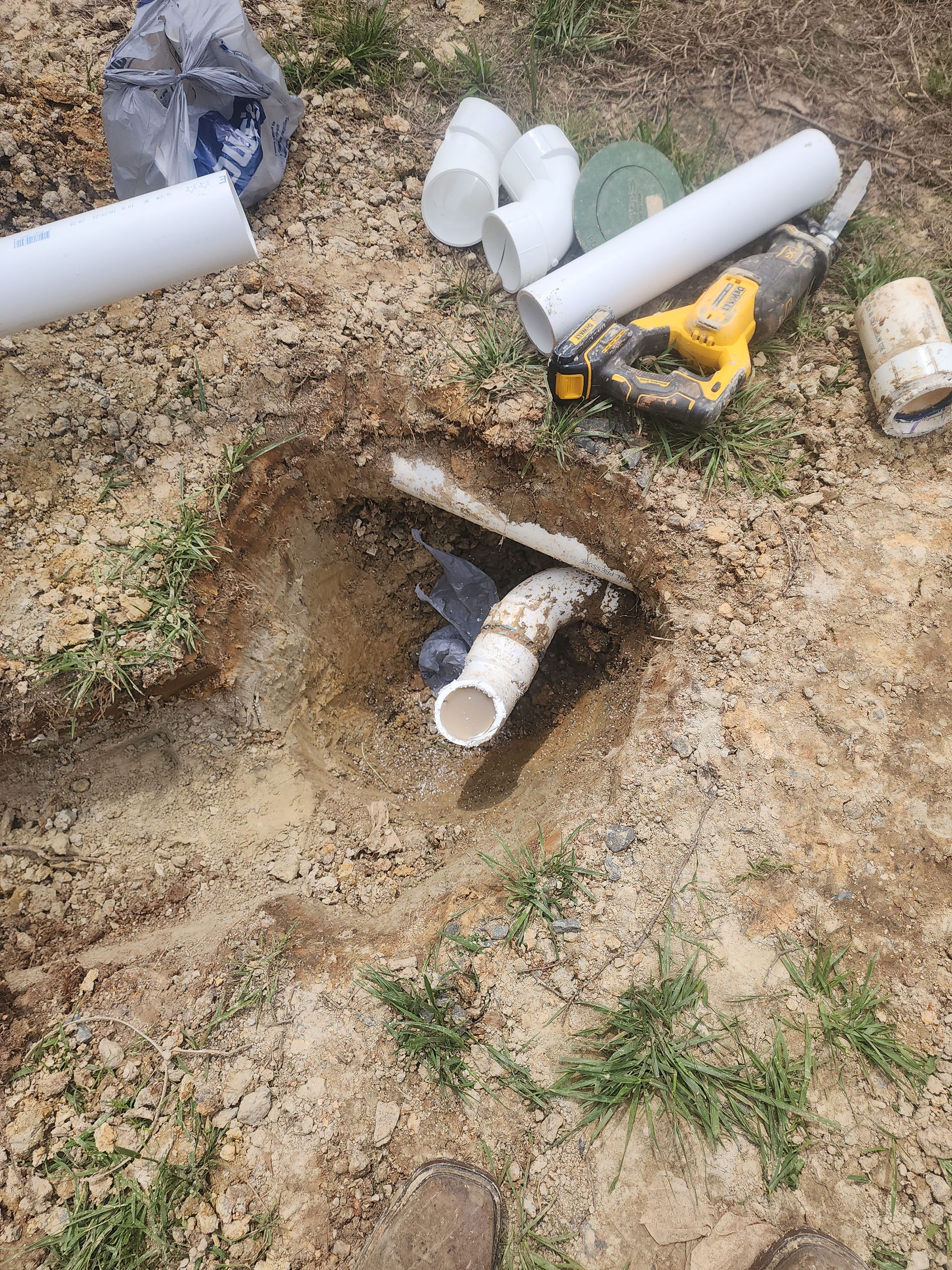 A bunch of pipes are laying on the ground in a hole.
