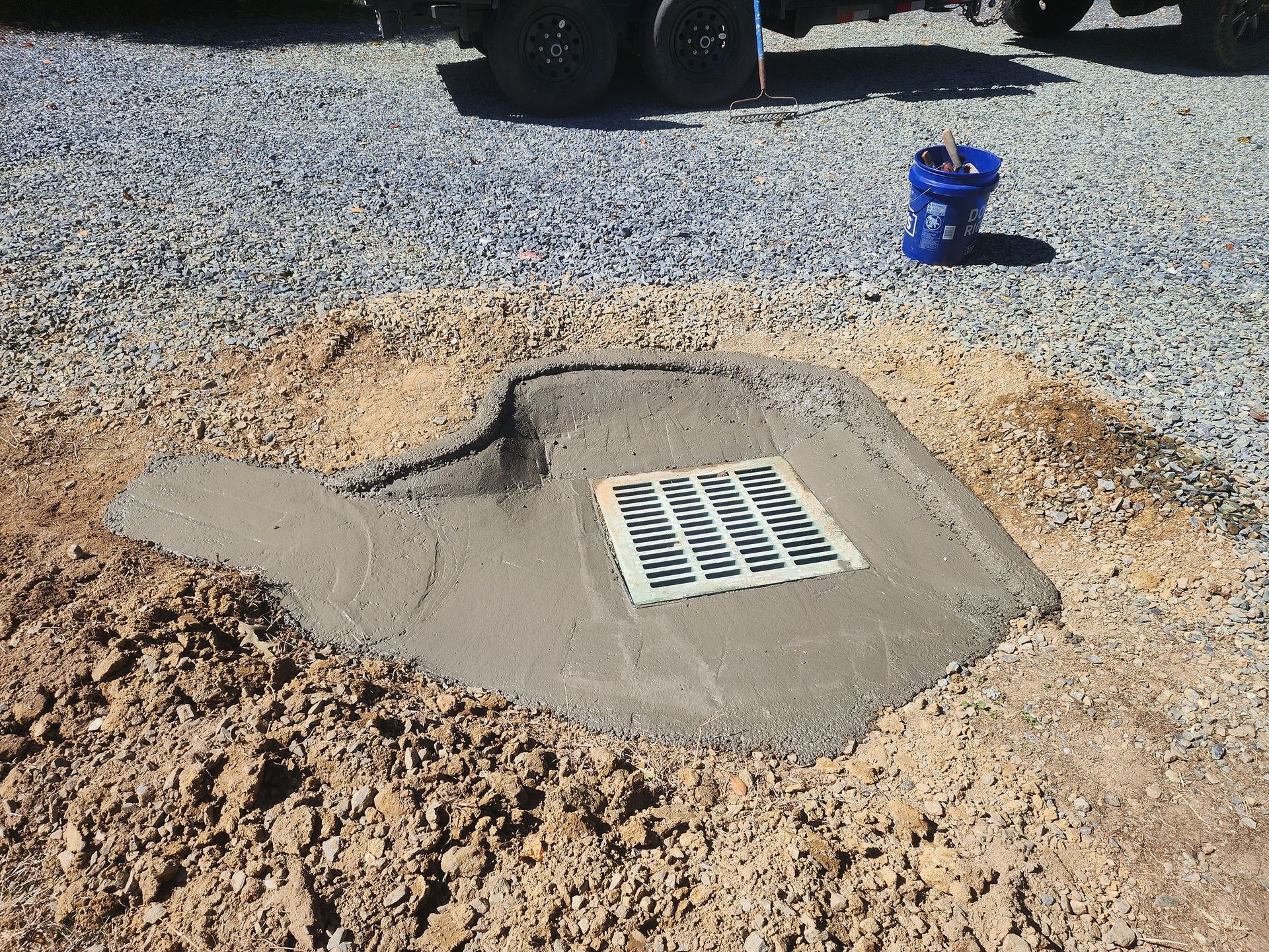 A blue bucket sits next to a hole in the ground