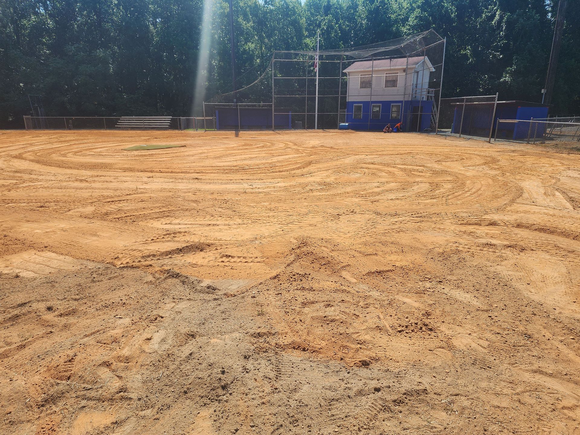 A large dirt field with a house in the background