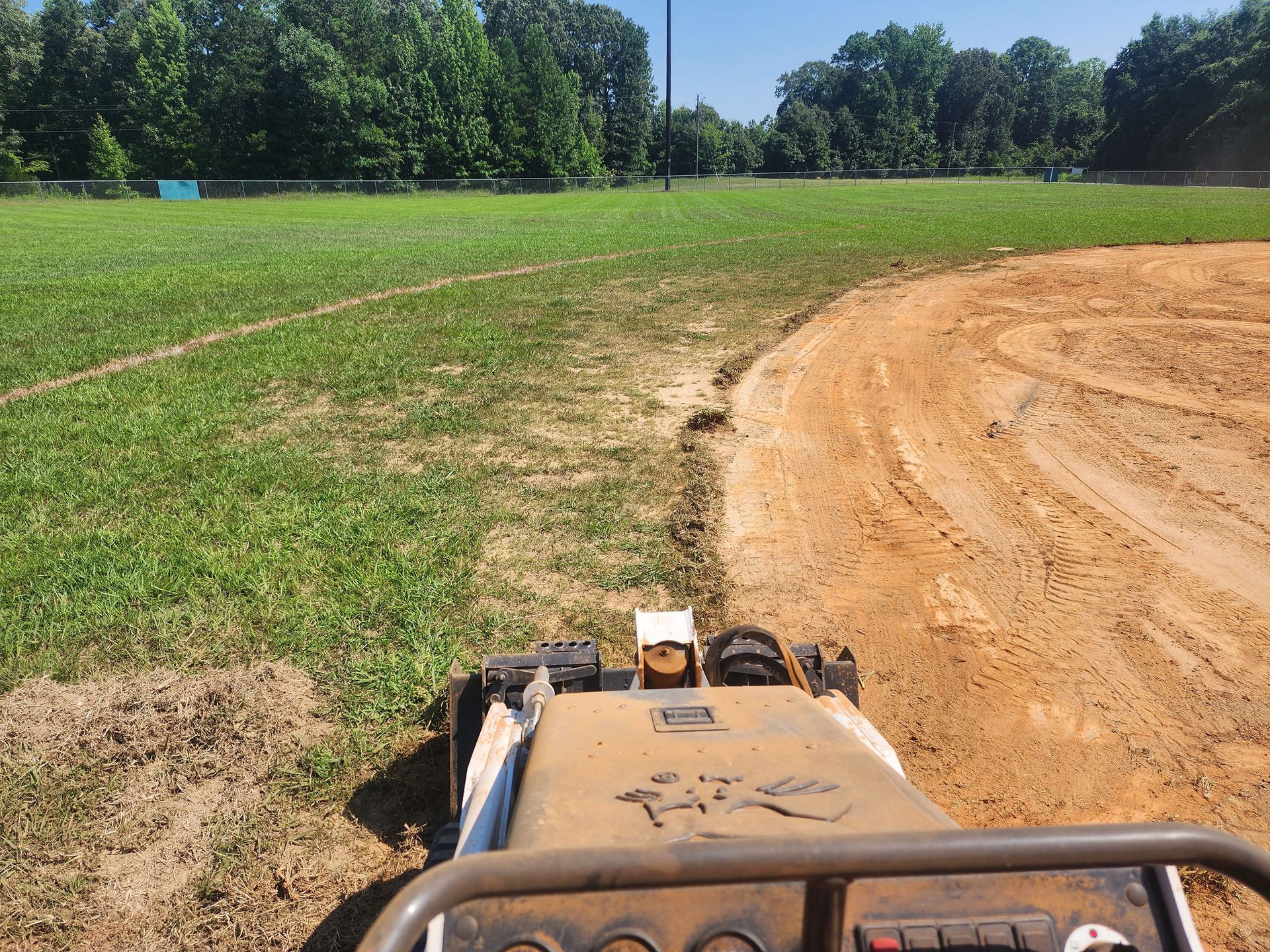 A tractor is driving down a dirt road in a field