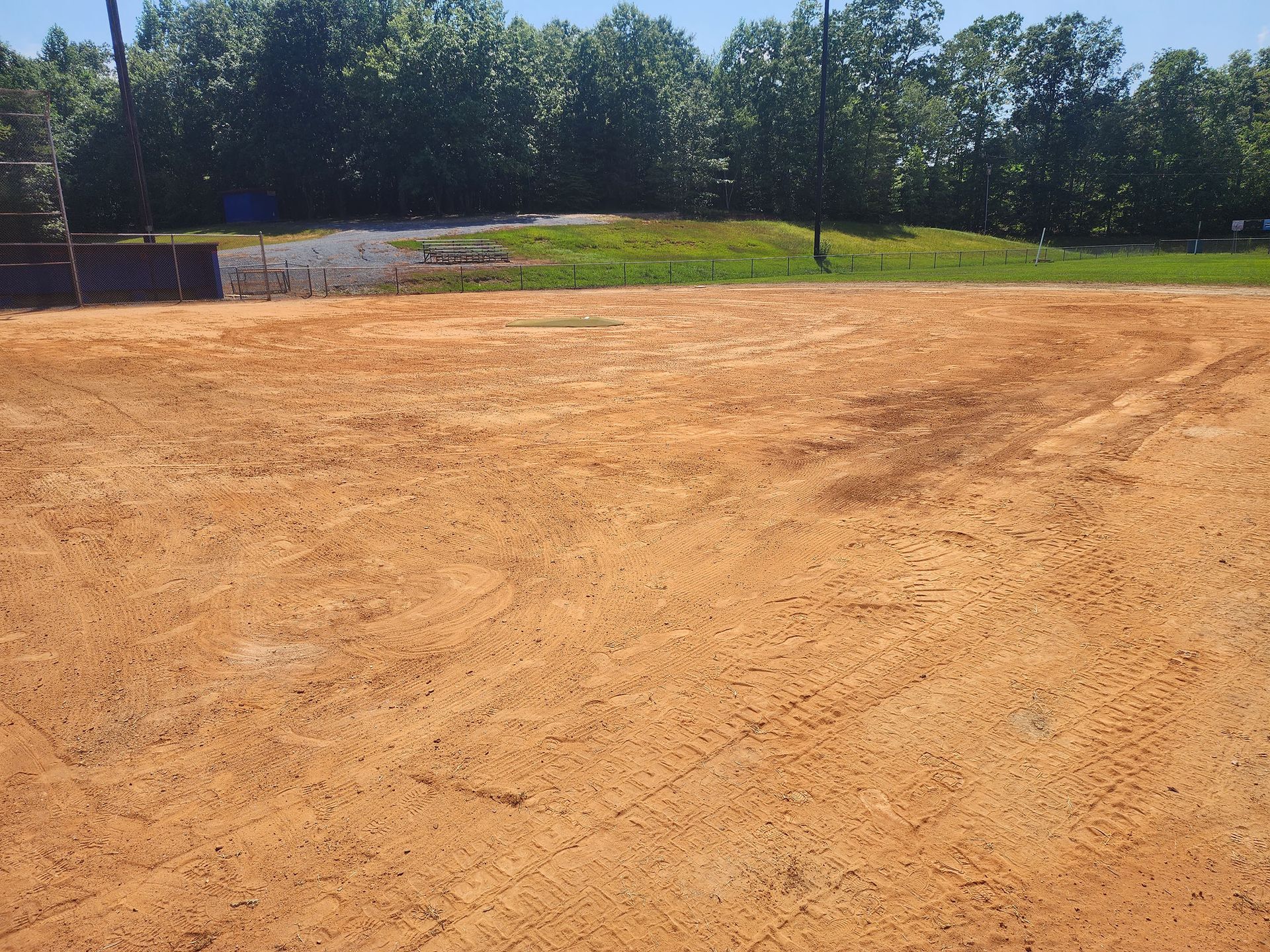 A field with a lot of dirt and trees in the background