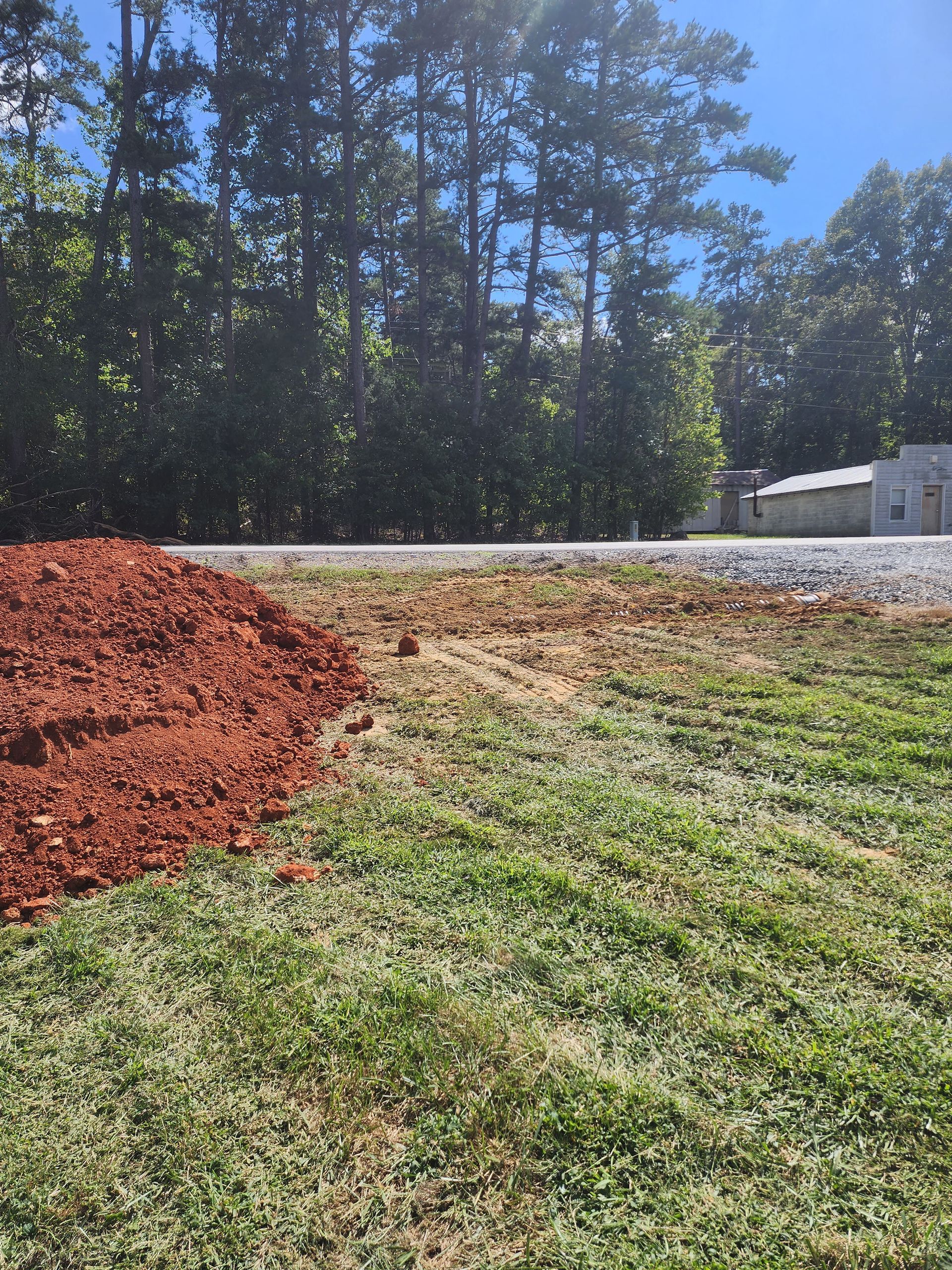 A large pile of dirt is in the middle of a grassy field.