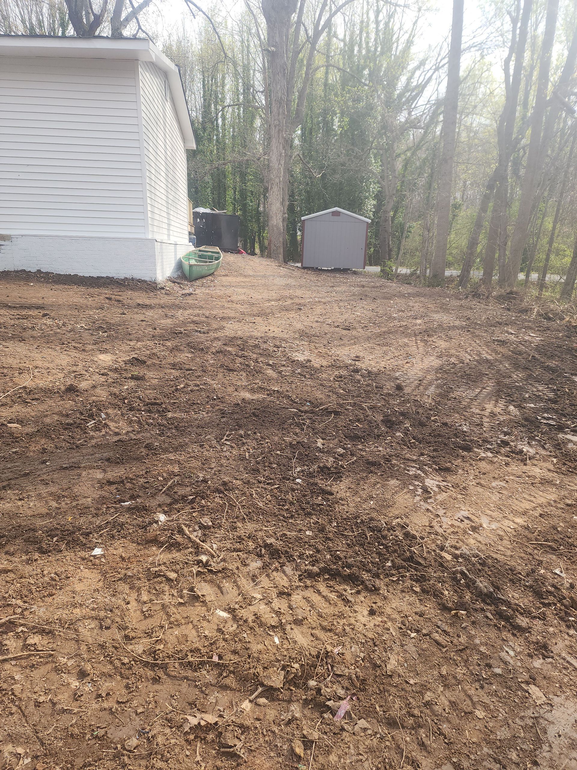 There is a white house in the background and a lot of dirt in the foreground.