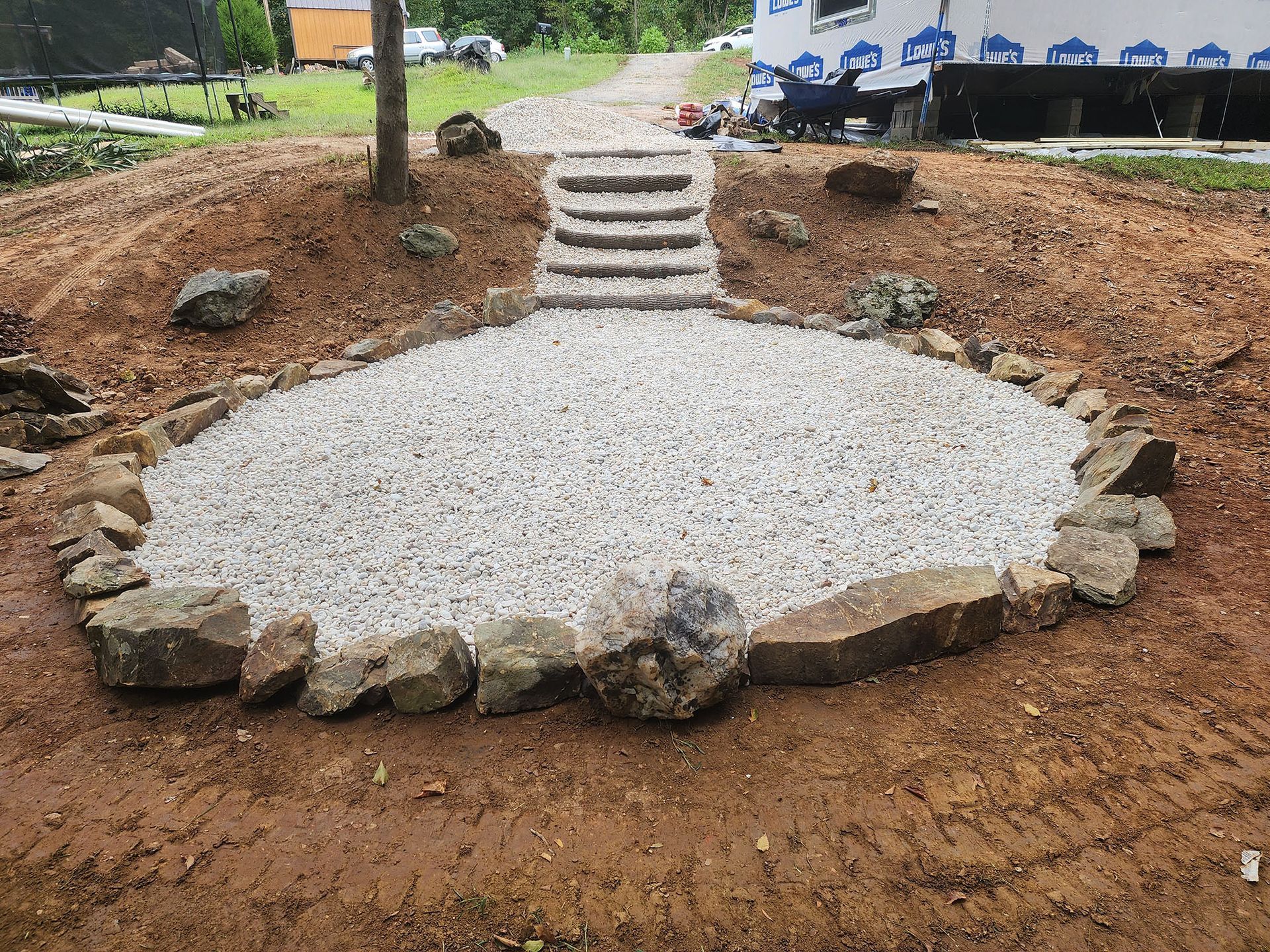 A circular area filled with gravel and rocks with stairs leading to it.
