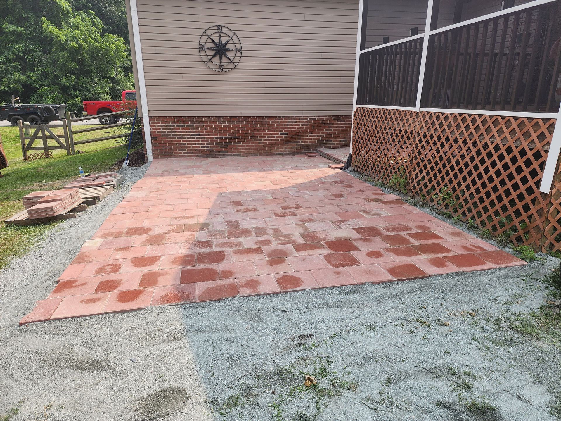 A brick patio is being built in front of a screened in porch.
