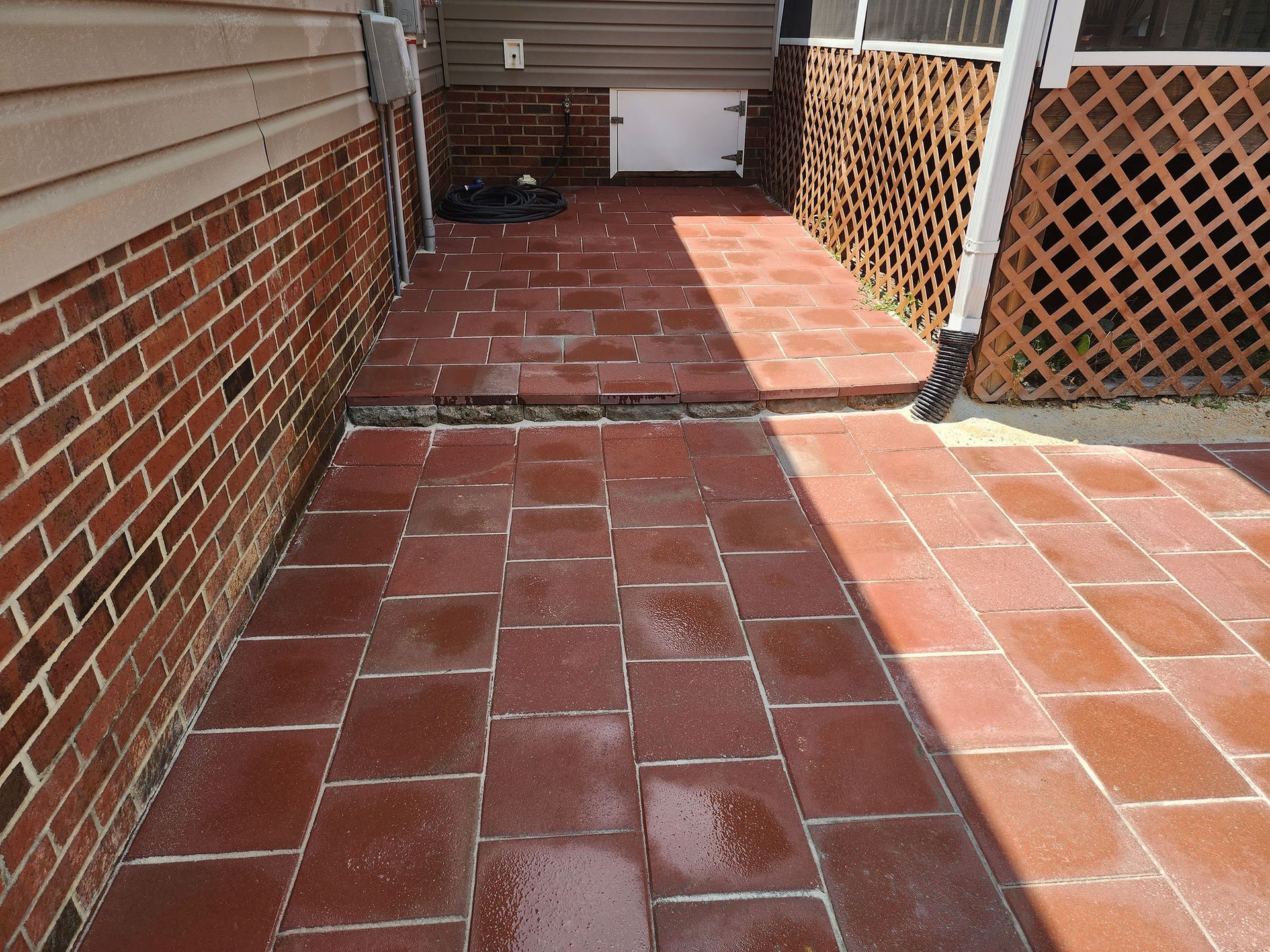 A brick walkway leading to a screened in porch next to a brick wall.