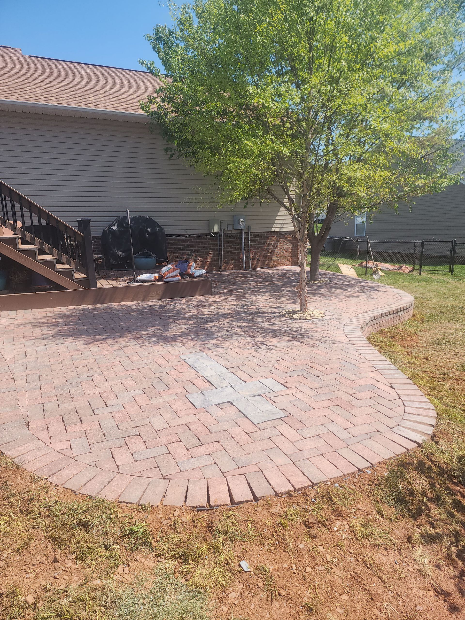 A brick walkway leading to a house with a deck and stairs.