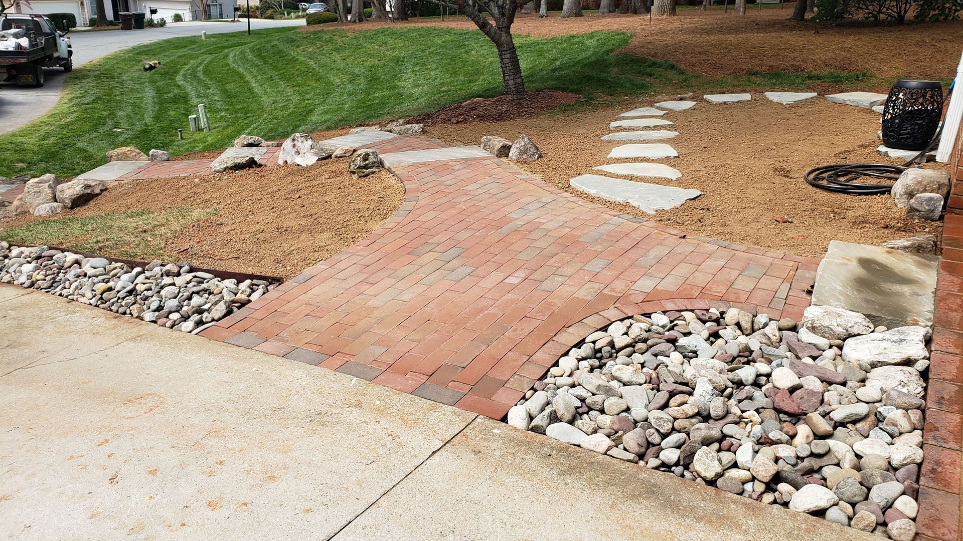 A brick walkway surrounded by rocks and gravel in a yard.
