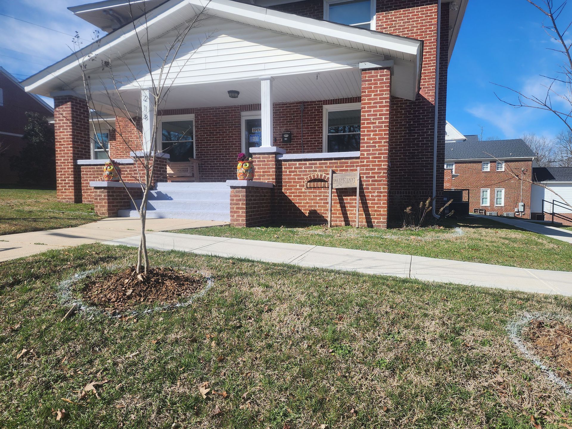 A brick house with a porch and a tree in front of it