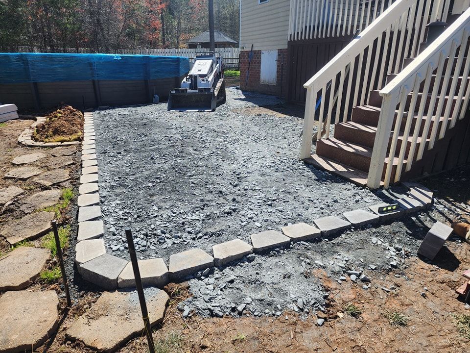 A patio is being built in front of a house with stairs.